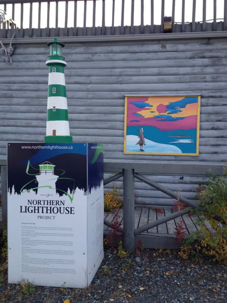 Mini Northern lighthouse in front of Northern painting of  Aurora Borealis in Yellowknife Canada