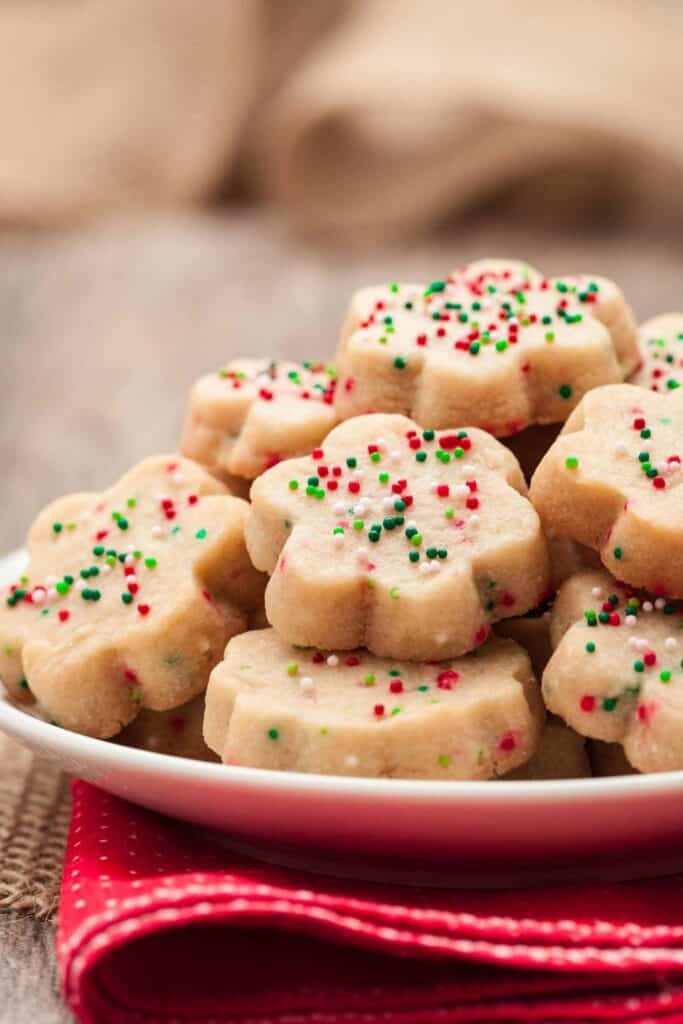 Close up of a plate of shortbread cookies with green, white and red sprinkles. 