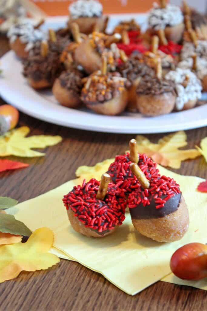 Donut holes decorated with chocolate,  sprinkles and pretzel sticks to look like acorns.