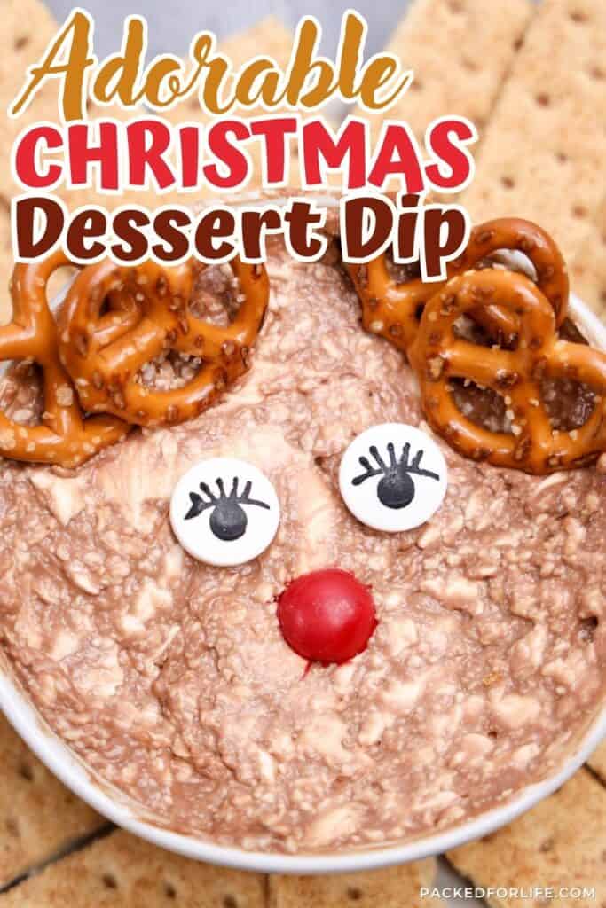Close-up of a festive chocolate dessert made to look like a reindeer with pretzel antlers, candy eyes, and a red candy nose, served as a fun Christmas party dip for holiday gatherings.