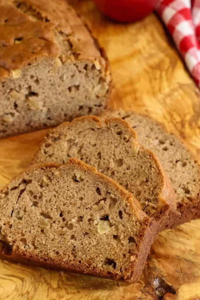 Three slices of Apple Cinnamon Bread lying on a wooden cutting board. 