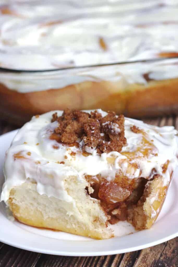 Plate with apple crumble cinnamon roll iced. 