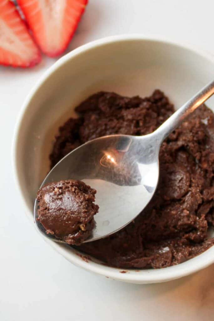Spoonful of chocolate fudge in a bag over a bowl. 
