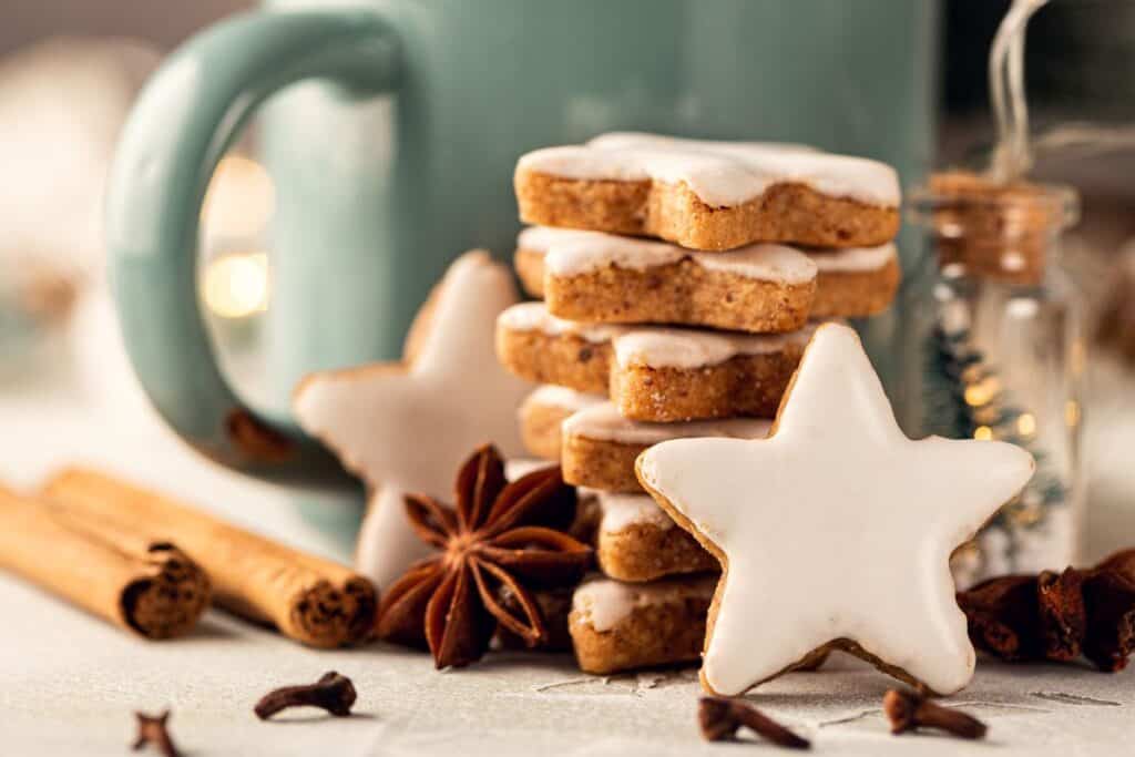 Authentic German gingerbread cookies in the shape of stars stacked beside a coffee mug.