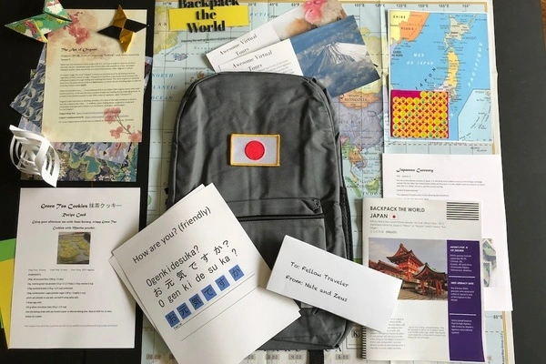 Backpack the World travel subscripion box with backpack, maps, crafts and travel guide laid flat.