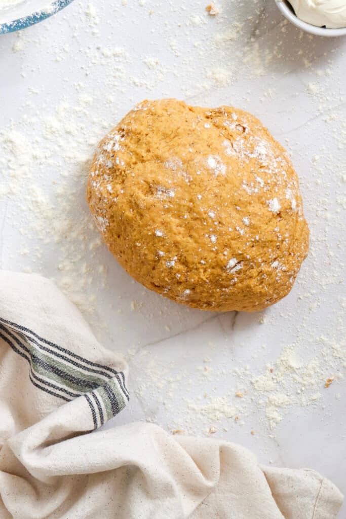 Ball of Pumpkin Cinnamon Roll Dough on a floured marble surface