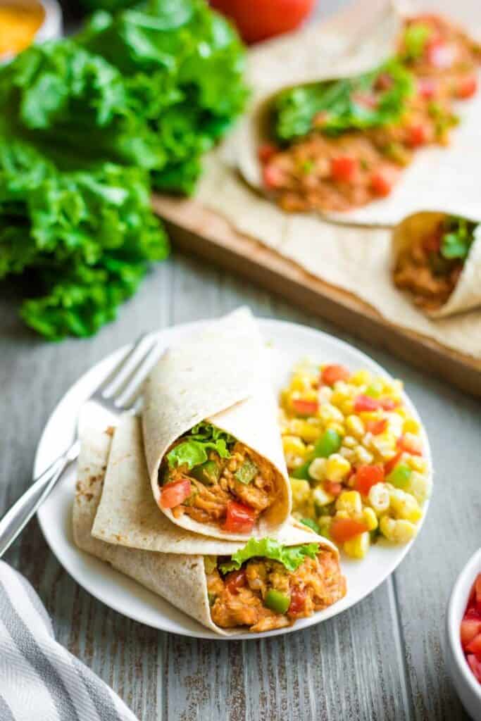 BBQ chicken wrap on a plate with corn salad.