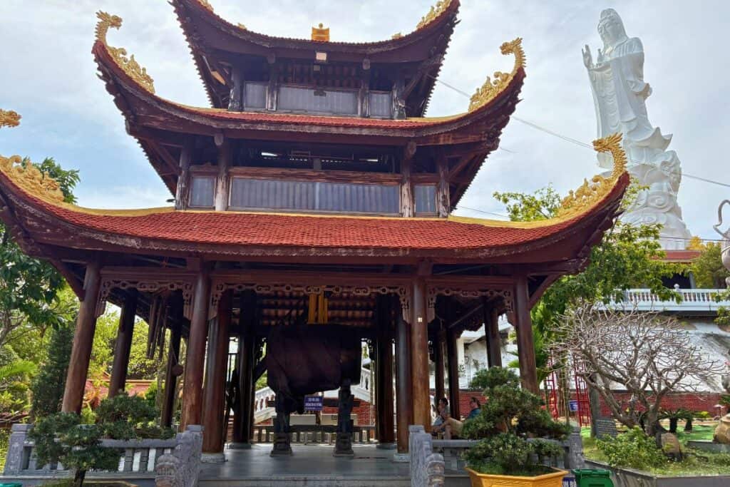 Bell Tower with Asian architecture, and a large white Quan Yin statue at the Ho Quoc Temple complex on Phu Quoc. 