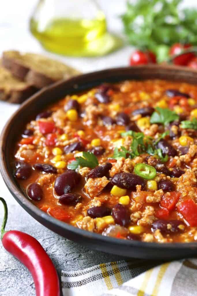 Cose up of a bowl of crockpot chili with black beans, corn, meat and tomatoes. 