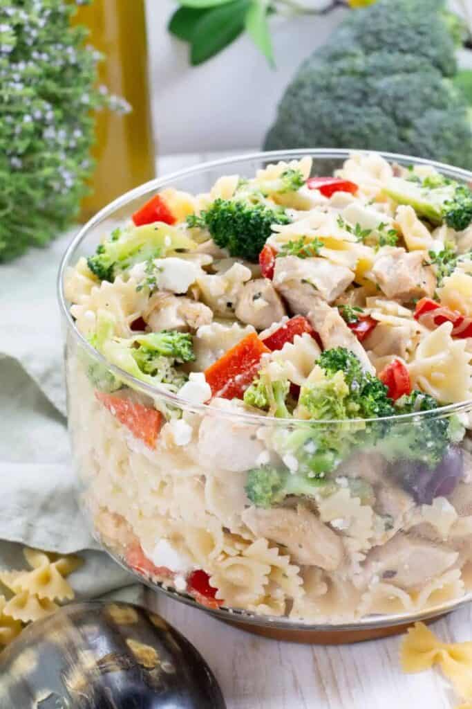 Glass conatiner of chicken, broccoli pasta salad with penne pasta, red bell peppers, and kalamata olives. 