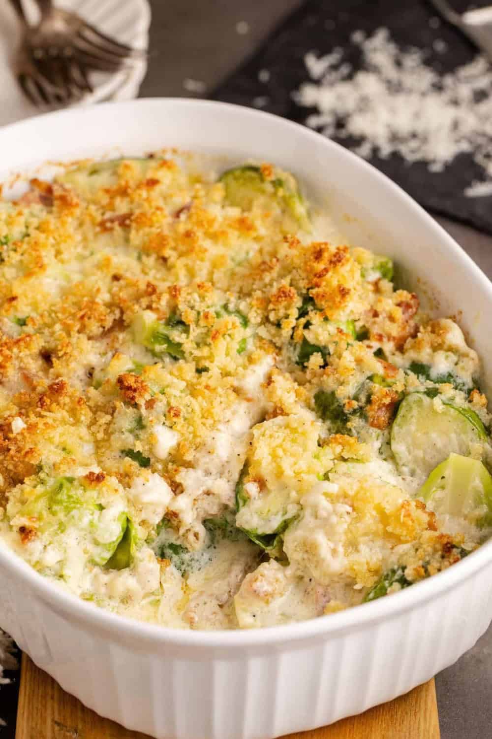 A white baking dish filled with creamy Brussel Sprout Casserole, with tender halved Brussels sprouts in a rich cheese sauce and a crispy golden breadcrumb topping.