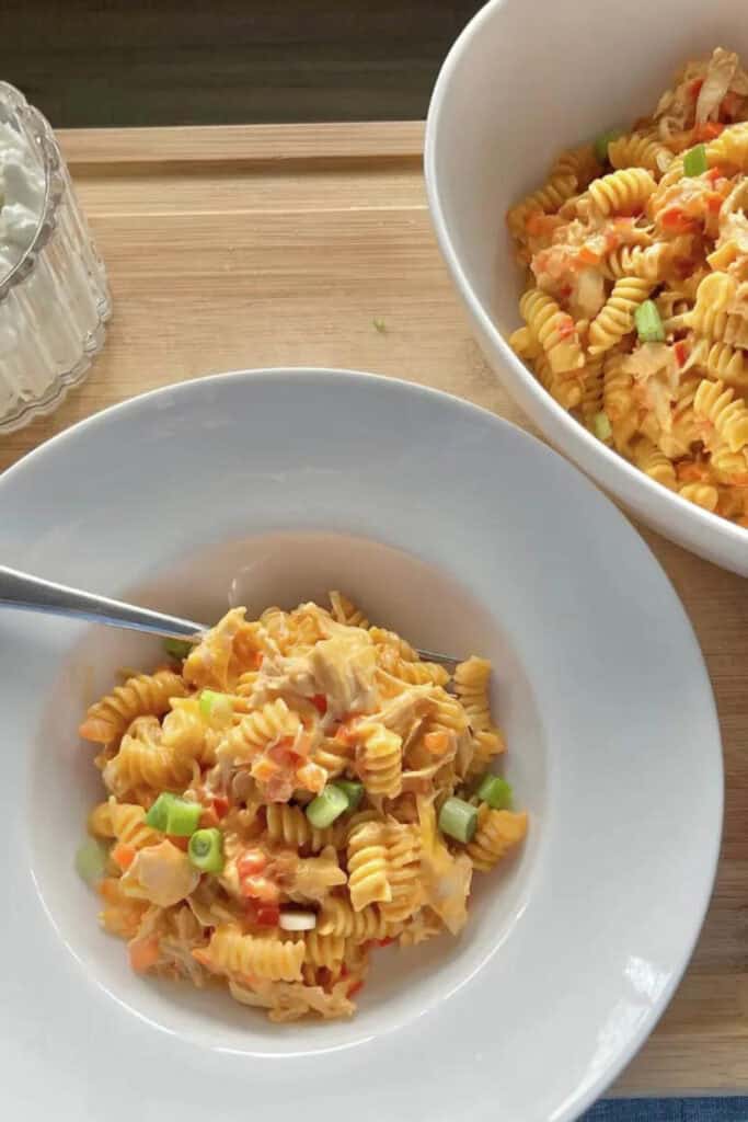 Bowl of buffalo chicken pasta with rotini, red peppers and green onions