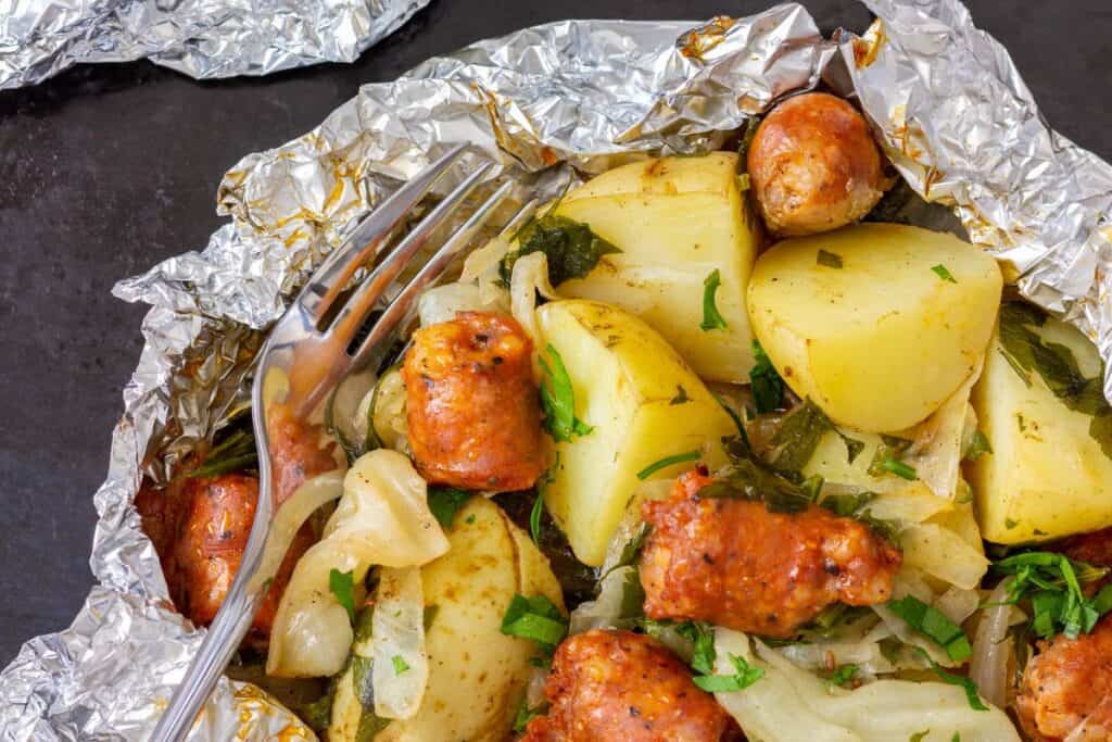 Camping Foil packet with potatoes and sausage bake and fork.