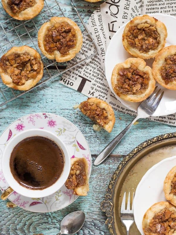 Butter tarts on a plate, and cooling rack beside a cup of coffee.