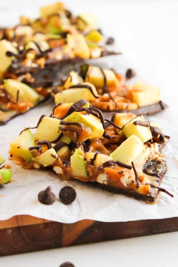 Chocolate bark topped with chopped green apples, Caramel, Pretzel piece, Pecans And chocolate drizzle for a simple fall dessert.