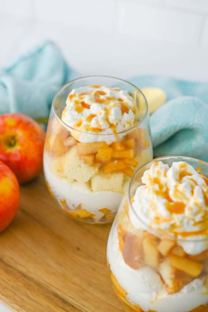 Two individual Caramel Apple Trifle Christmas Desserts layered with tender apples, cubes of cake, and whipped cream, then topped with caramel sauce.