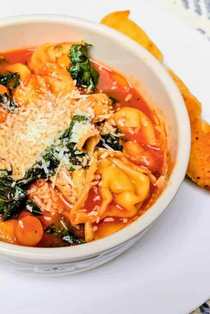 heese tortellini soup with leafy greens and tomatoes is served in a rich tomato broth. Grated Parmesan cheese tops the tortellini for a hearty finish.