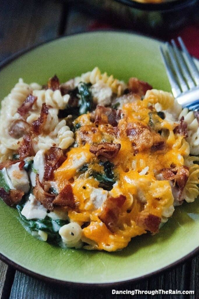 Plate of rotini pasta, chicken cheese, bacon and spinach casserole.