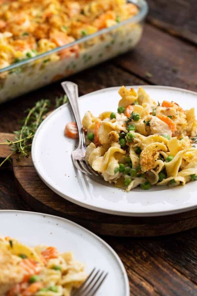 Two plates of chicken noodle casserole with carrots & peas. 