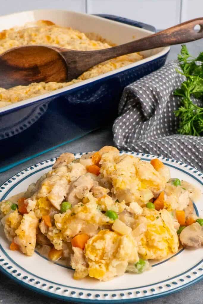 Chicken pot pie casserole with tender chicken, peas, carrots, potatoes and mushrooms in a creamy sauce topped with golden biscuits, a cozy choice for easy cold weather dinner ideas.