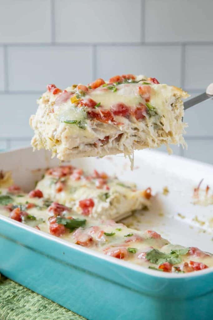 Serving spoon holding a square of chicken tortilla casserole. 