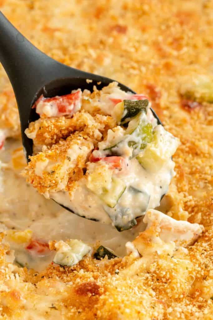 Spoon of creamy zucchini, chicken casserole with panko topping. 