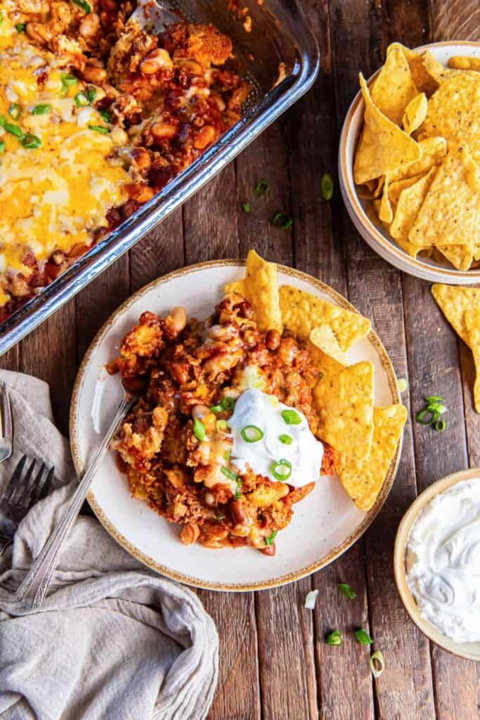 Hearty chili cornbread casserole with beans, melted cheese and green onions served with sour cream and tortilla chips.