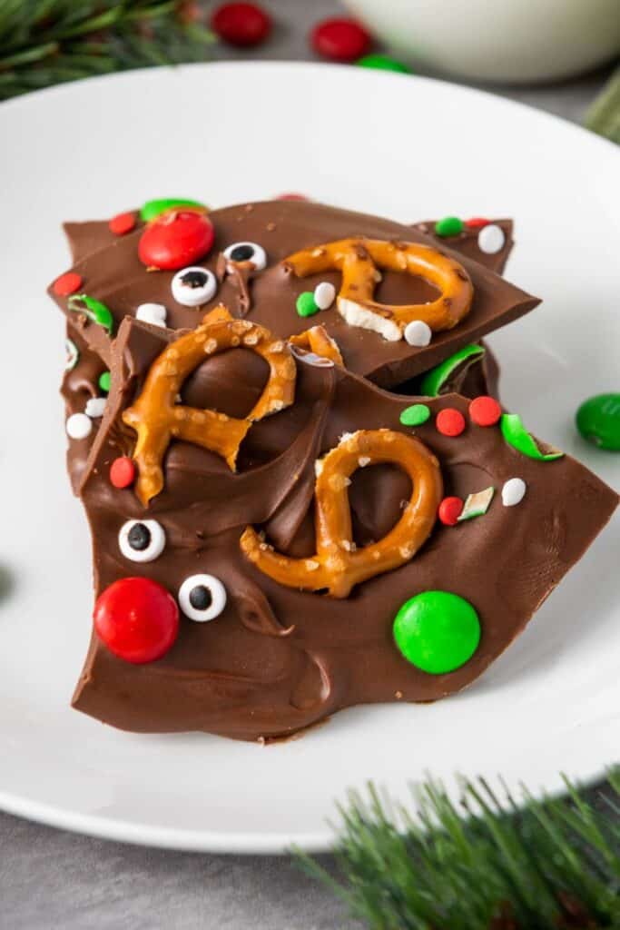 Close up of chocolate Rudolph reindeer Christmas bark with pretzel antlers, candy eyes, red M&Ms nose.