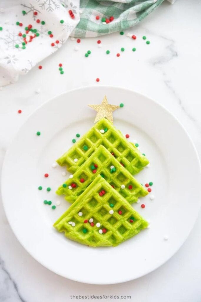 Green 1/4 waffles set out on a plate like a Christmas Tree with sprinkles.