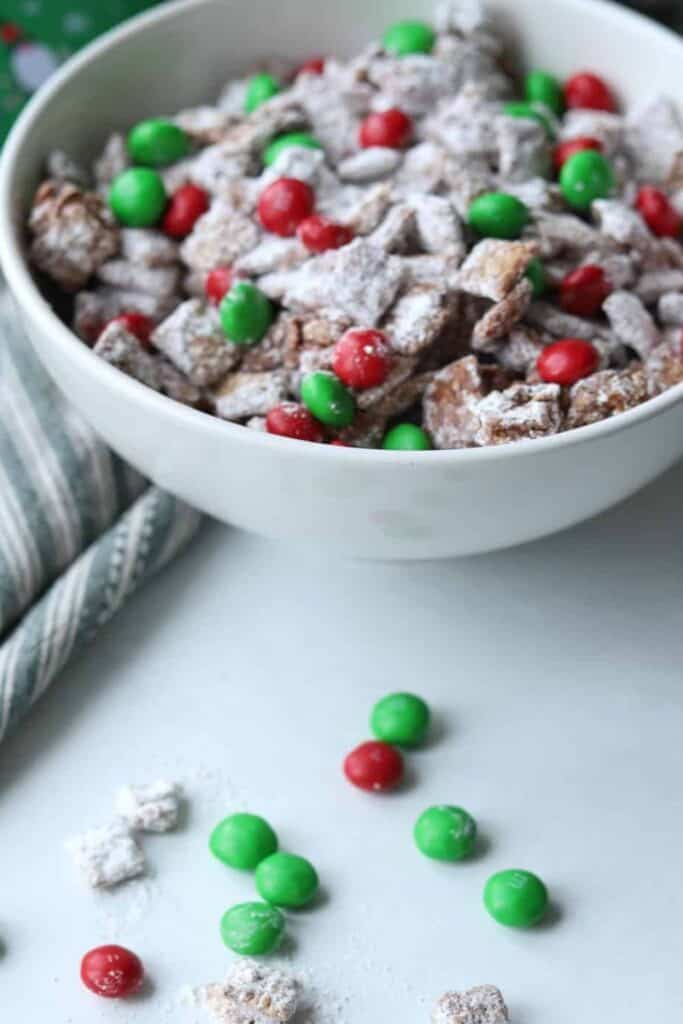 Close up a a bowl of Christmas Muddy Buddies with chex cereal and red and green M&M's.