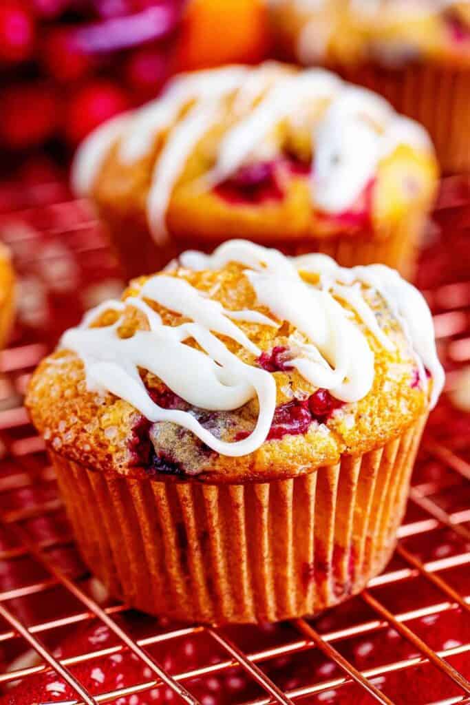 Two cranberry orange muffins drizzled with icing.