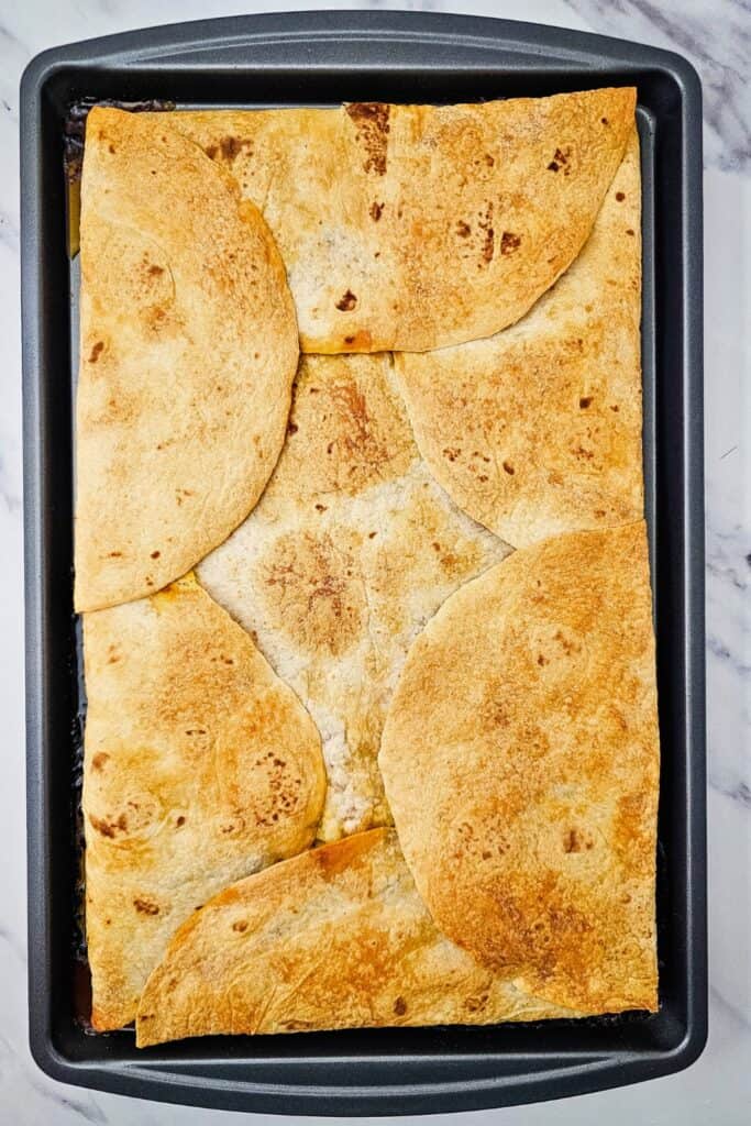 Freshly baked pan of crispy sheet pan quesadillas with golden brown tortillas forming a sealed top layer for an easy family dinner. 