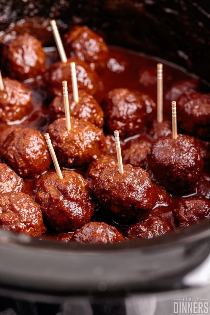 Bowl of crockpot BBQ meatballs with toothpicks sticking out of them. 