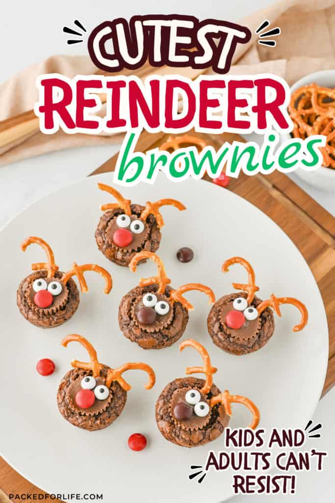 Plate of festive reindeer brownies made with round chocolate brownie bases, mini peanut butter cups for snouts, candy eyes, red or brown chocolate candies for noses, and twisted pretzels for antlers. Styled on a white plate with extra pretzels and candies around, captioned “Cutest Reindeer Brownies” and “Kids and adults can’t resist!”