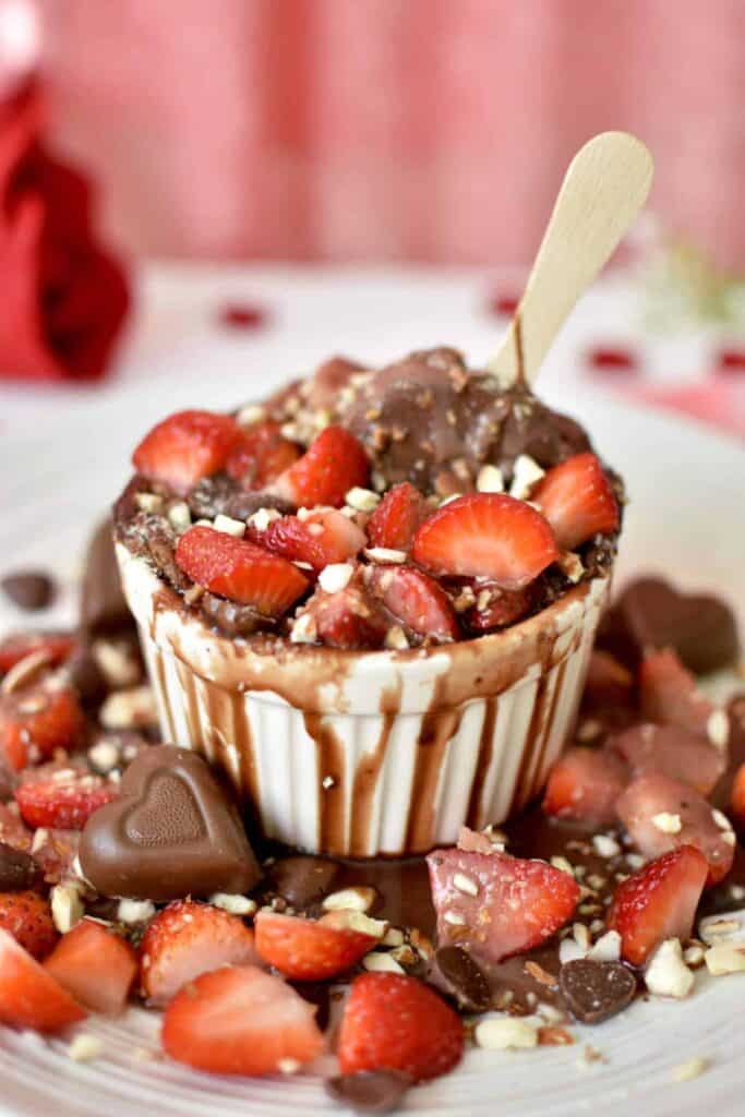 Ramekin of chocolate souffle topped with strawberries and heart chocolates. 