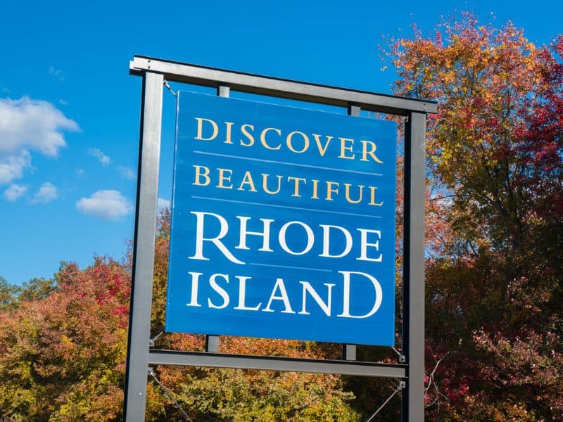 Discover Beautiful Rhode Island sign in front of trees with colorful fall leaves. 