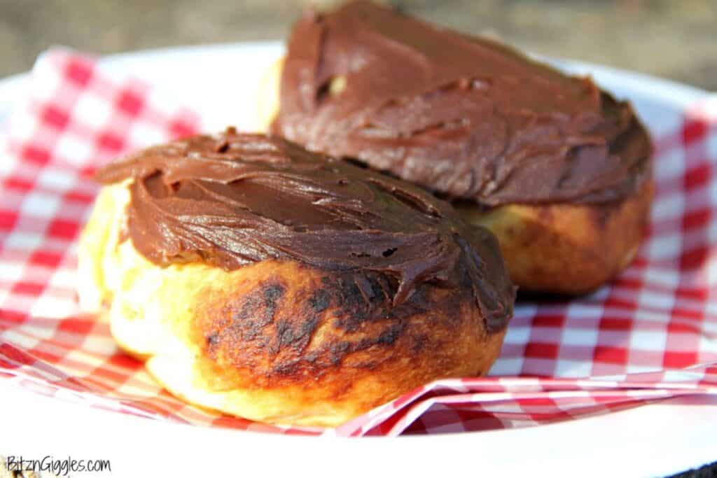 Two campfire eclairs with chocolate frosting on a plate. 