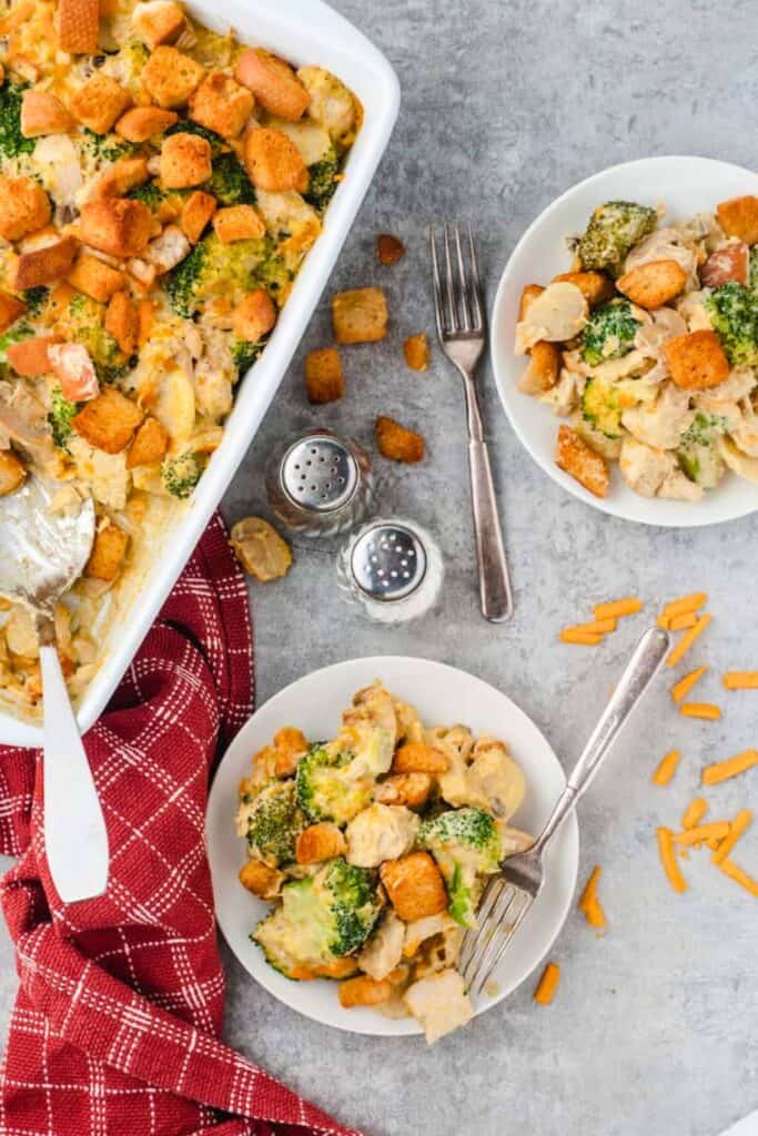 Creamy chicken and broccoli casserole with tender chicken pieces, broccoli florets, melted cheese and golden croutons, served in white bowls for a hearty fall harvest casserole.