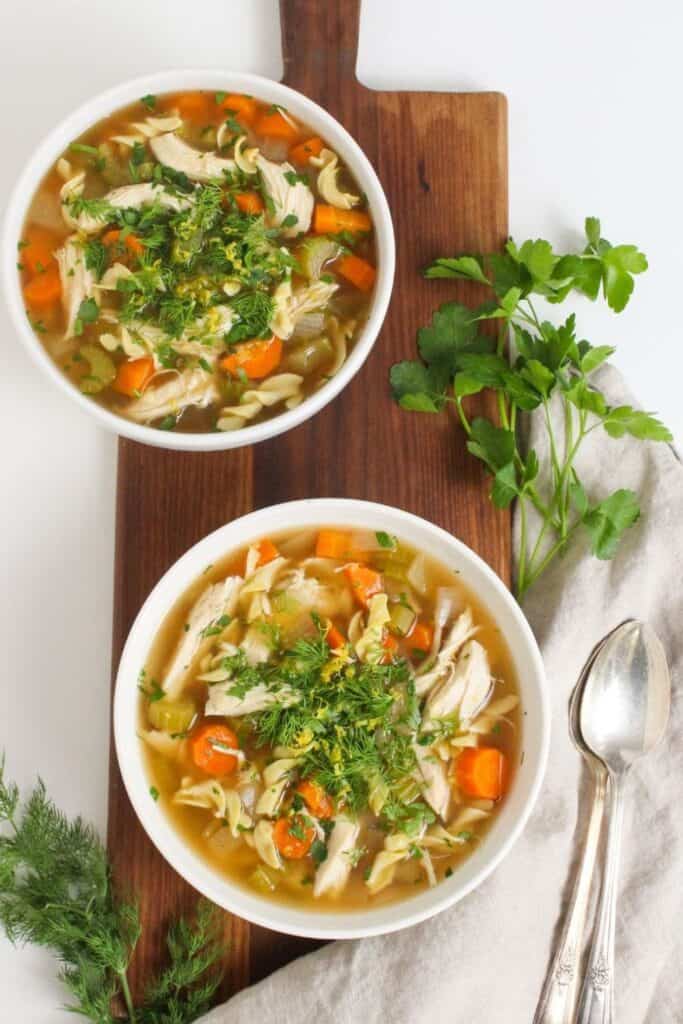 Two bowls of easy crockpot chicken soup with carrots and celery. 