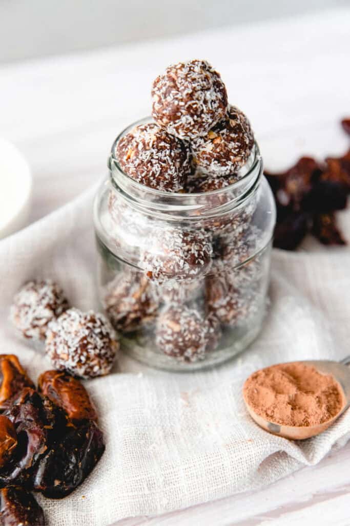 Glass jar filled with coconut, date, almond protein balls. 