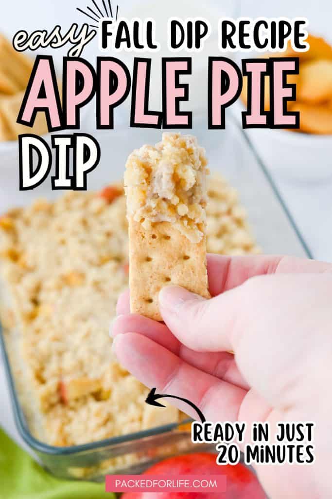 Pinterest Pin of a Hand holding a cracker topped with warm, crumbly apple pie filling from a glass baking dish. Text overlay reads Easy Fall Dip Recipe: Apple Pie Dip ready in just 20 minutes.