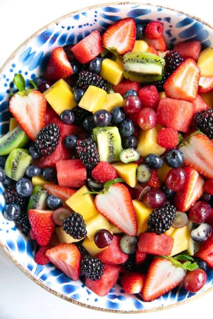 Colorful bowl of fruit salad with strawberries, kiwis, grapes, blueberries, mango.