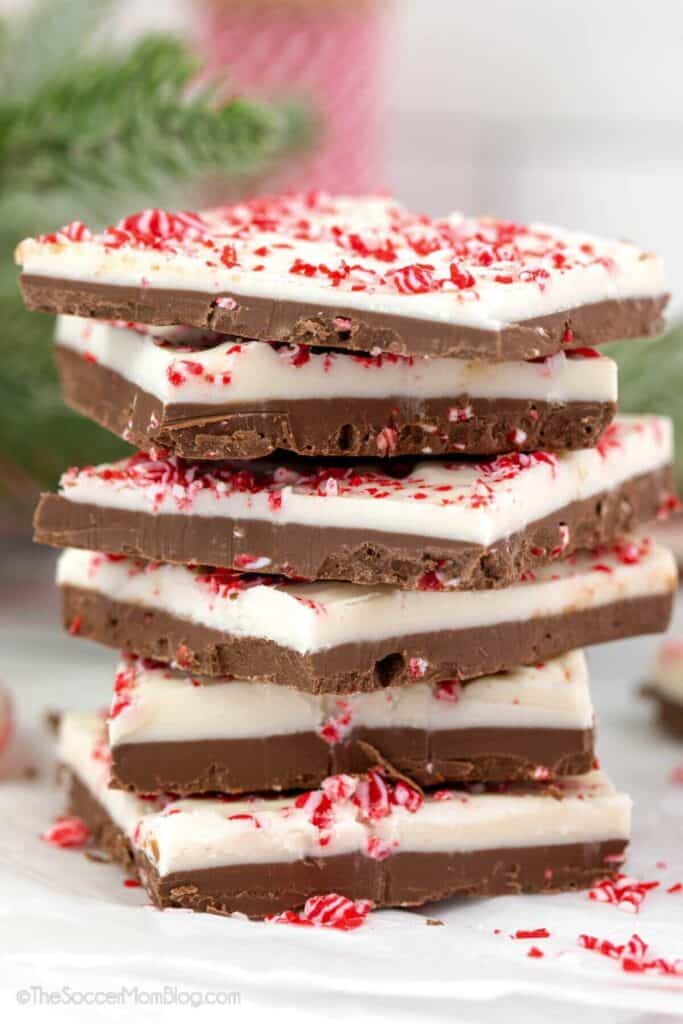 Stack of easy peppermint bark made with layers of dark and white chocolate, topped with crushed peppermint candies. The festive red and white topping adds a holiday touch to this classic no-bake Christmas treat.