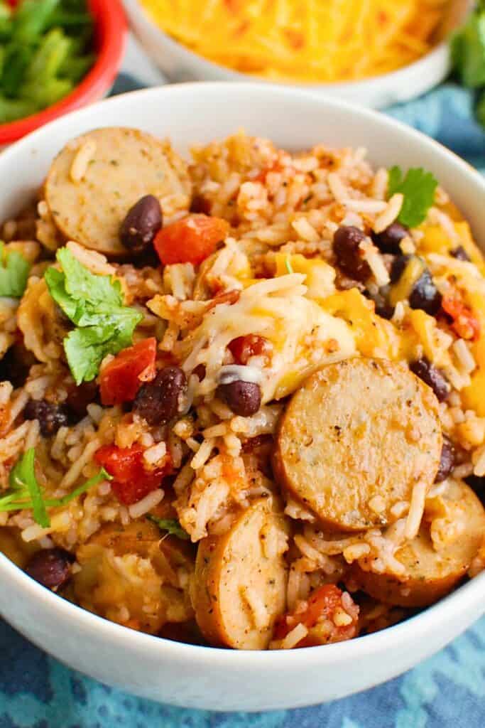 Sausage and rice casserole with sliced sausage, black beans, diced tomatoes, melted cheese and fresh cilantro, a hearty option for Fall Potluck Casseroles.