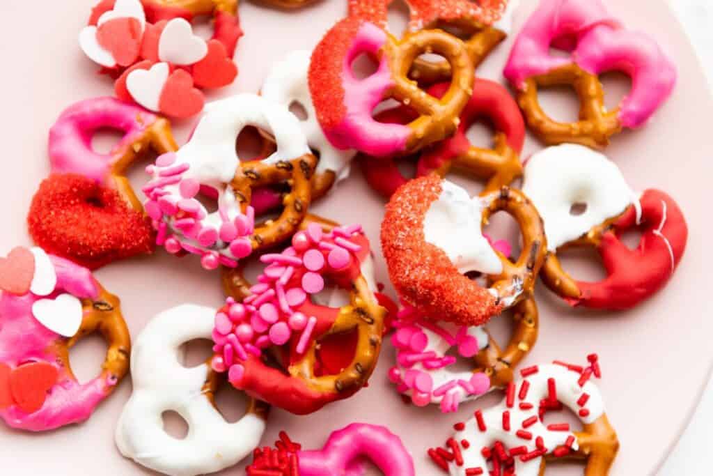 Close up of a pile of Valentine's themed pretzels dipped in red, pink and white candy with sprinkles.