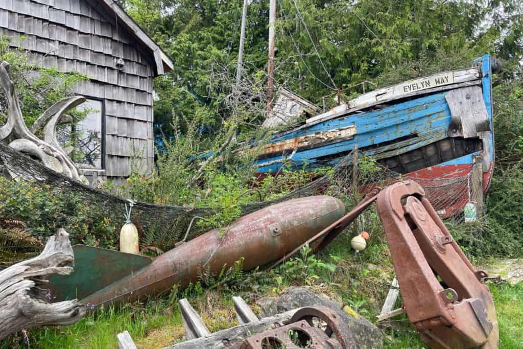 Decrepit boat a, anchor beside a wooden building. 