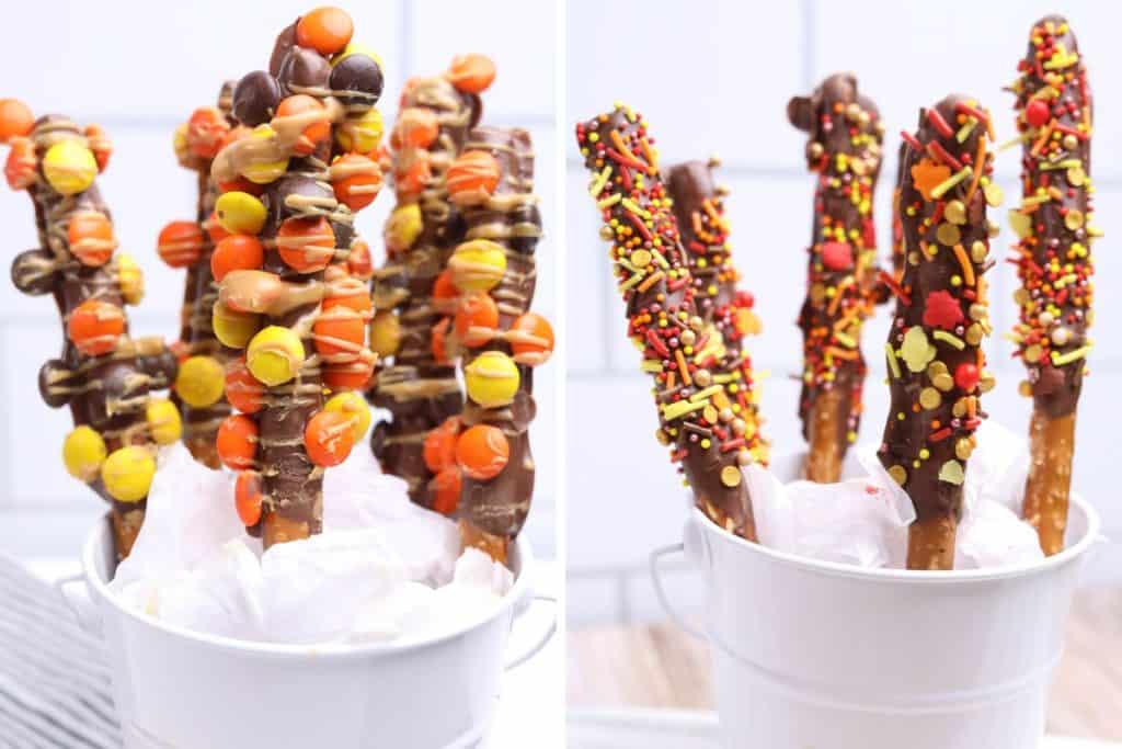 Side-by-side display of Fall Chocolate Covered Pretzels in white pails, with one set topped with Reese’s Pieces and peanut butter drizzle, and the other decorated with colorful fall sprinkles. Both variations feature chocolate-dipped pretzel rods arranged upright in festive autumn style.