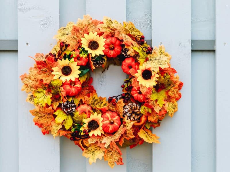 Autumn wreathe with artificial sunflowers, pumpkins and maple leaves.