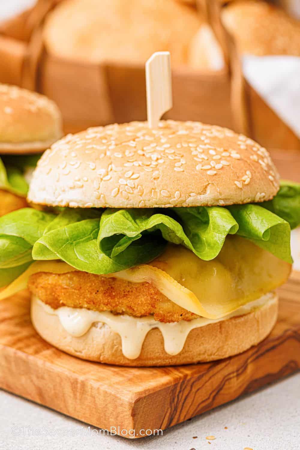 Crispy breaded fish fillet topped with melted cheese, crisp lettuce, and creamy tartar sauce on a sesame seed bun, served on a wooden board. This Filet-O-Fish copycat recipe recreates the classic fast food sandwich with a golden, crunchy fish fillet and simple toppings.