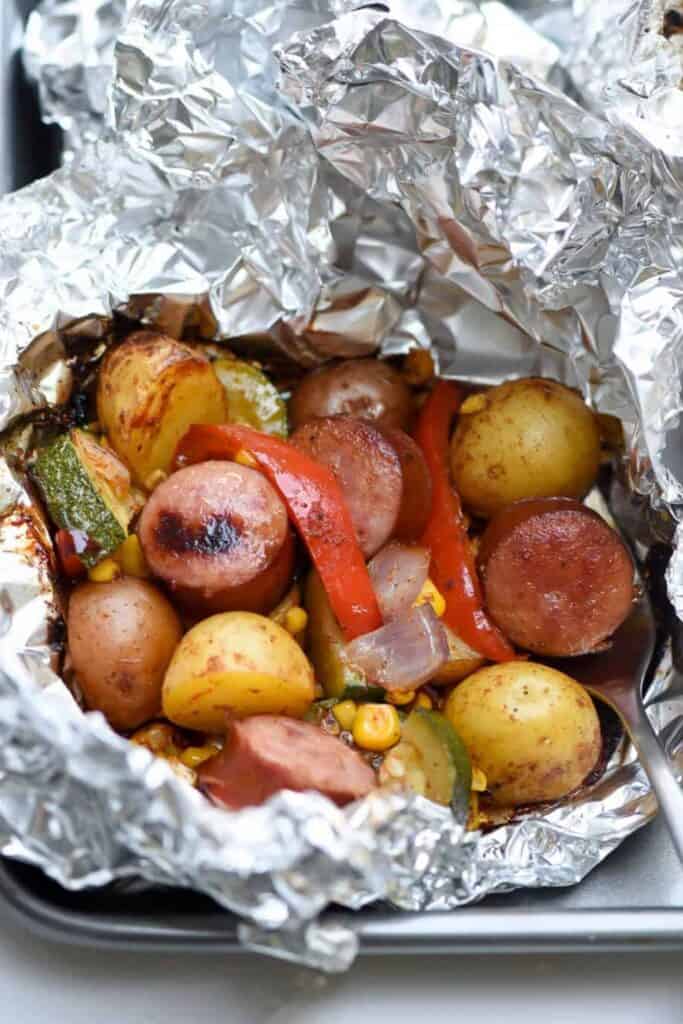Overhead view of a sausage, potato and red pepper foil packet camping breakfast. 